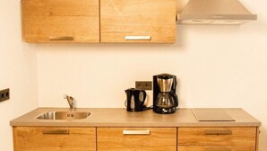 Una cocina con armarios de madera, un lavamanos de acero inoxidable y una cafetera.