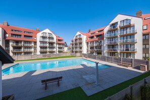 A modern apartment complex with a central swimming pool, multiple balconies, and a well-maintained lawn. - Cosy Apartment Near the Center (Middelkerke)