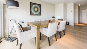 A modern dining area with a wooden table, white chairs, and a pendant lamp.