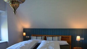 Ein Doppelbett mit weißer Bettwäsche, einem Holzkopfstück und zwei Nachttischlampen.