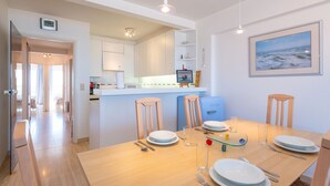 Een moderne keuken met witte kasten, een blauwe koelkast en een eethoek met een houten tafel gedekt voor vier personen.