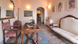 A room with a wooden table, a sofa, a patterned rug, and a brick ceiling. - Belvilla by OYO Michelangelo (Castiglion Fiorentino)