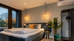 A modern bedroom with a large bed, two pendant lights, a potted plant, and a built-in wardrobe. - Cozy House in Koudekerke Near the Beach (Koudekerke)
