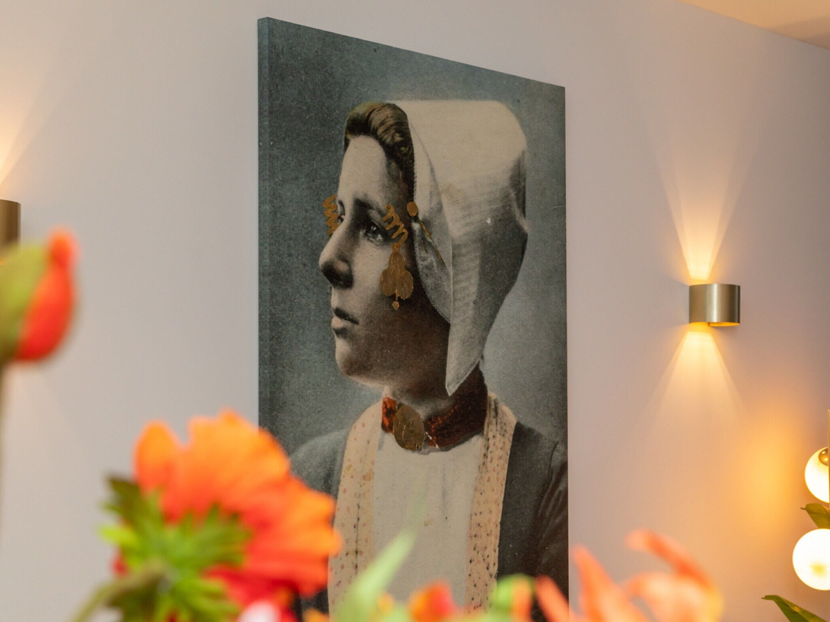 Un portrait d’une femme portant un foulard, accroché au mur.