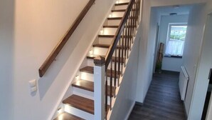 Eine Treppe mit Holzbodenstufen und weißen Geländern, die zu einer oberen Etage führt.