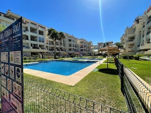 A swimming pool area with a signboard listing amenities and rules.