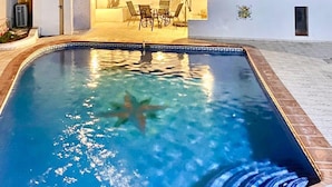 Une piscine décorée d’une étoile de mer, entourée d’une terrasse carrelée et d’un espace patio aménagé avec du mobilier d’extérieur.