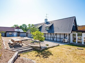 A residential property with a large house, a smaller attached building, and a patio area with outdoor seating.