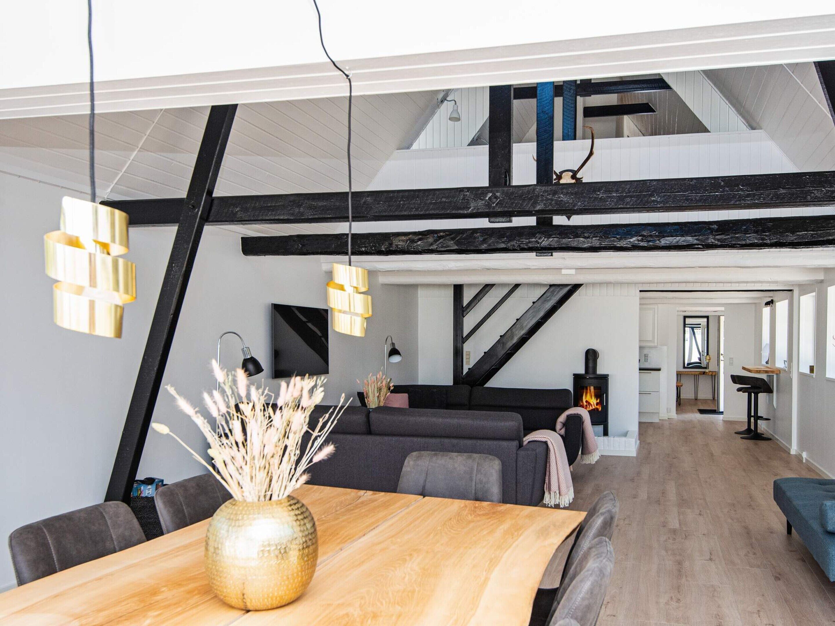 Um interior moderno com área de jantar, sofá e lareira.