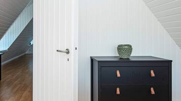 A room with a wooden floor, a black filing cabinet with leather handles, and a white door.