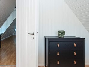 A room with a wooden floor, a black filing cabinet with leather handles, and a white door.
