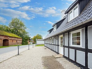 A traditional building with a gravel pathway leading to a white door, surrounded by a cobblestone area. - 10 Person Holiday Home in Auning (Auning)