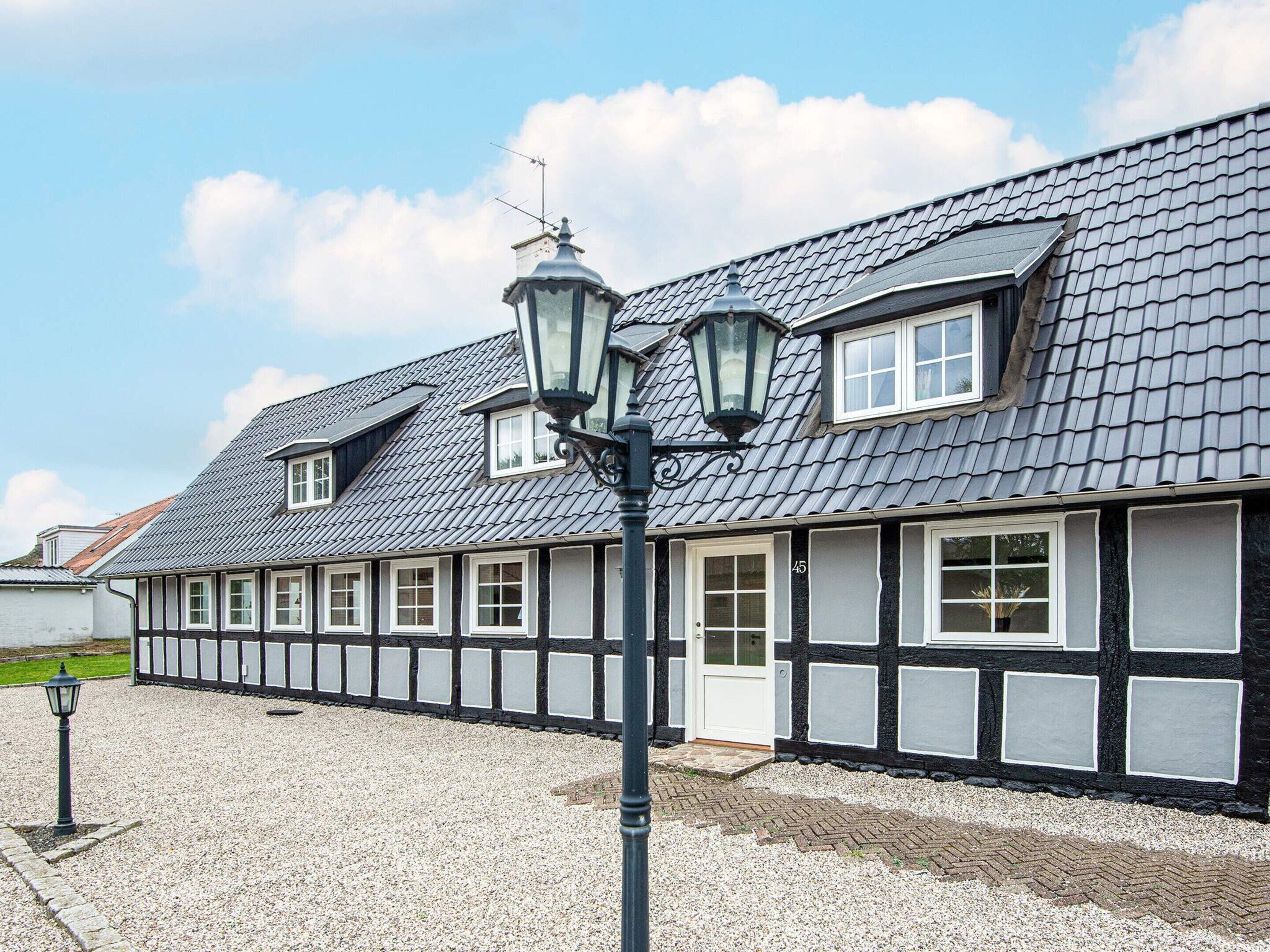 A traditional building with a gabled roof, multiple windows, and a gravel driveway.
