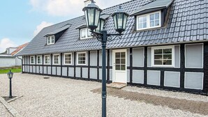 Un bâtiment traditionnel avec un toit à pignon, de nombreuses fenêtres et une allée gravillonnée.