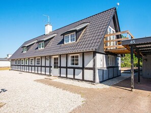 A traditional half-timbered house with a sloped roof, a wooden porch, and a gravel driveway.