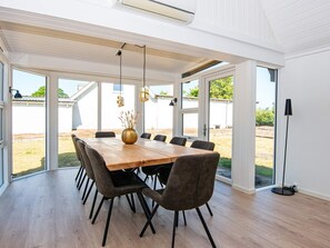 A spacious dining area with a wooden table and chairs, large windows, and a view of the outdoors. - 10 Person Holiday Home in Auning (Auning)