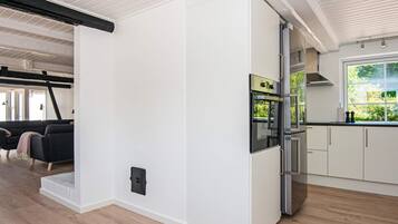 A modern kitchen with white cabinetry, a built-in oven, and a window overlooking greenery.