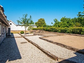 A building with a gravel courtyard, wooden benches, and a small tree. - 10 Person Holiday Home in Auning (Auning)