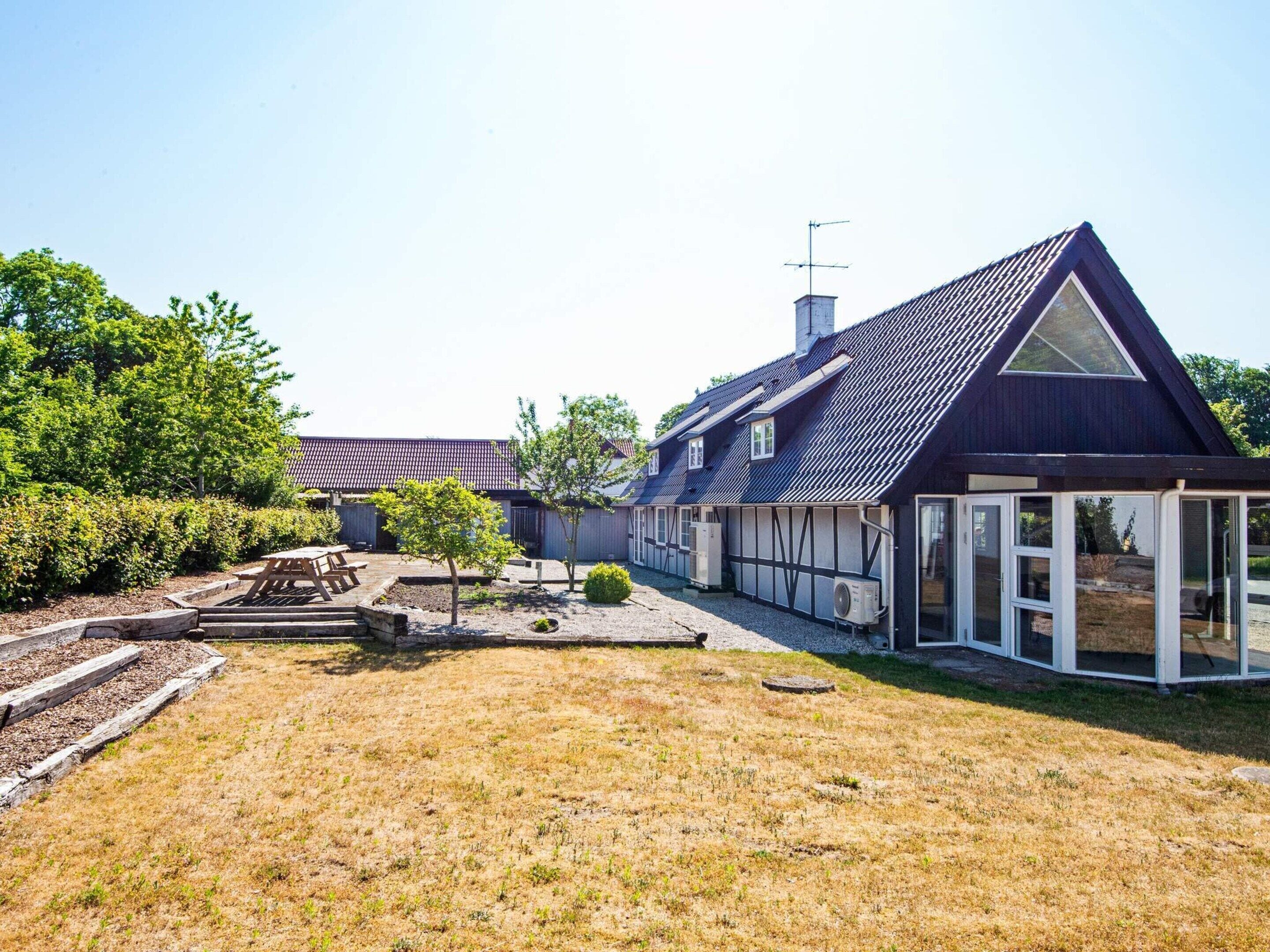 A residential property with a large house, a covered patio, and a well-maintained lawn.