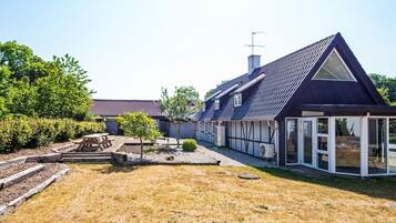 A residential property with a large house, a covered patio, and a well-maintained lawn.