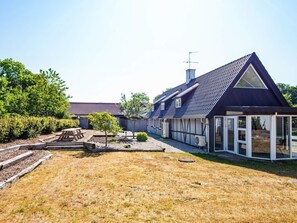 A residential property with a large house, a covered patio, and a well-maintained lawn.