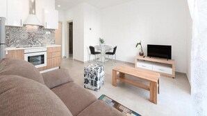 A modern living room with a sofa, a coffee table, a TV, and a small dining area with a table and chairs. - Apartments Bella Vista - One Bedroom Apartment With Terrace (Kastav)