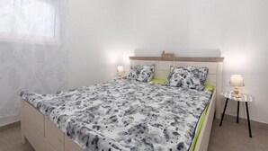 A bedroom with a bed, two bedside lamps, a headboard with the word "Dream," and a window with a patterned curtain. - Apartments Bella Vista - One Bedroom Apartment With Terrace (Kastav)