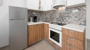 A compact kitchen with a refrigerator, coffee maker, stove, and patterned backsplash. - Apartments Bella Vista - One Bedroom Apartment With Terrace (Kastav)