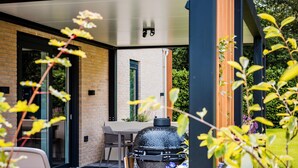 Ein Patio mit Grill, Tisch und Stühlen, umgeben von einer Backsteinmauer und Glastüren.