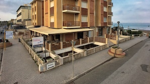 A multi-story hotel with outdoor seating, a visible restaurant, and a beach view. - Apartment Near Marina Castagneto Beach (Castagneto Carducci)