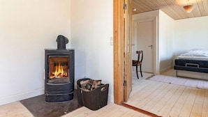 Ett rum med en vedeldad kamin, en säng och en dörr som leder till ett annat rum.