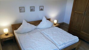 A double bed with white bedding, two bedside tables with lamps, and three framed pictures on the wall. - \"seagull Street\" 21 Merchant (Wangerland)
