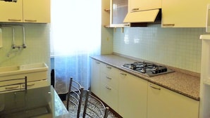 A small kitchen with white cabinets, a gas stove, and a microwave. - Apartment in Garda Near Lake (Garda)