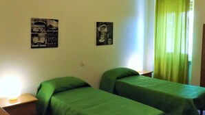 A room with two single beds, a small table, a lamp, and two posters on the wall. - Apartment in Garda Near Lake (Garda)