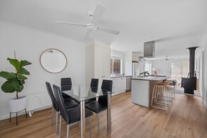 A modern kitchen with white cabinets, a central island with stools, and a ceiling fan. - Prom Coast - Duneside (Sandy Point)