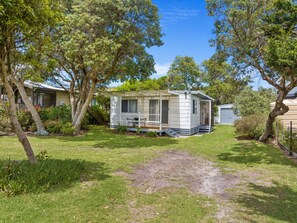 A mobile home with a porch and a small deck, surrounded by trees and a grassy yard. - Prom Coast - Duneside (Sandy Point)