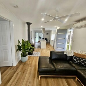 A modern living room with a black leather sofa, a ceiling fan, and a potted plant. - Prom Coast - Duneside (Sandy Point)