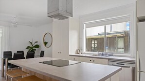 A modern kitchen with a central island, white cabinetry, and a window with a view of the outside. - Prom Coast - Duneside (Sandy Point)