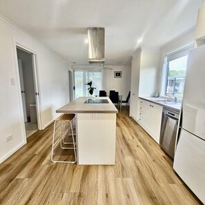 A modern kitchen with a central island, white cabinetry, and a stainless steel refrigerator.