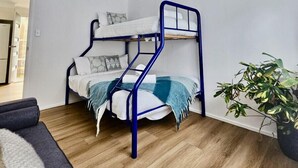 A bunk bed with a blue frame in a room with wooden flooring and a potted plant. - Prom Coast - Duneside (Sandy Point)