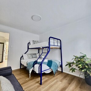 A bunk bed with a blue frame in a room with wooden flooring and a potted plant. - Prom Coast - Duneside (Sandy Point)