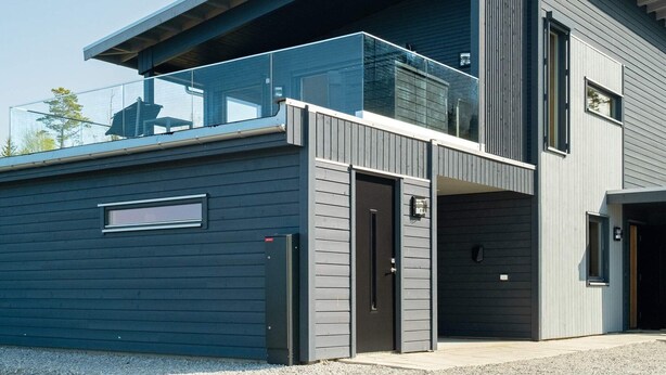 A modern two-story building with a garage door, a balcony with glass railings, and a large window on the upper floor. - 5 Star Holiday Home in Inderoy (Inderøy)