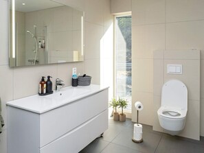 Une salle de bain moderne avec un meuble-lavabo blanc, un grand miroir, une douche et des toilettes.