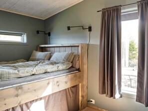 Une chambre avec un lit superposé en bois, une fenêtre avec des rideaux et deux lampes fixées au mur.