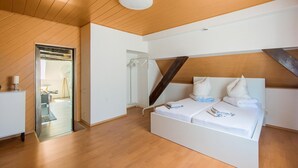 Un dormitorio moderno con techo de madera, cama blanca y vestidor.