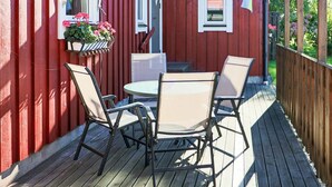 A red wooden deck with a round table and four chairs. - 8 Person Holiday Home in Skummeslovsstrand (Skummesloevsstrand)