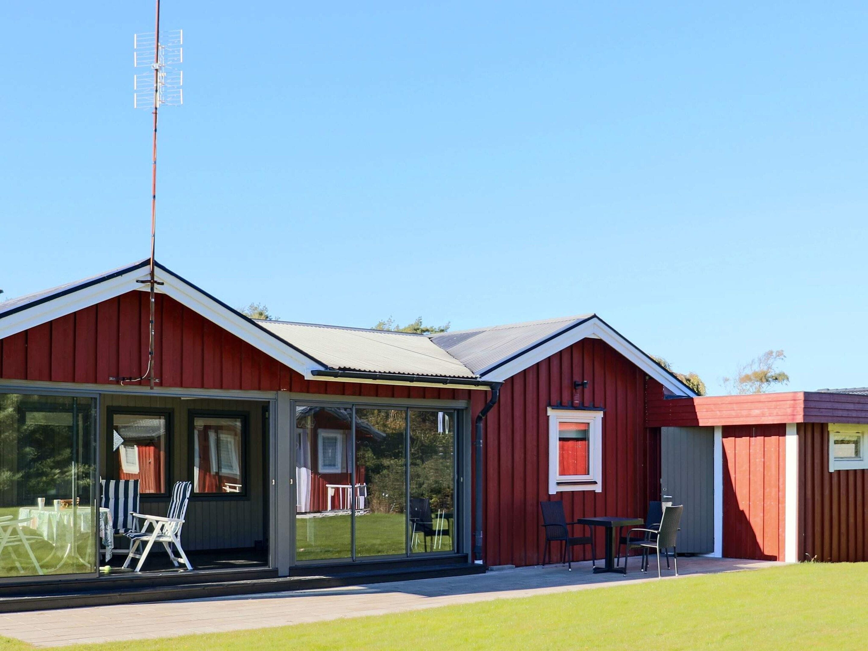 A red building with a glass enclosure, outdoor seating, and a clear sky.