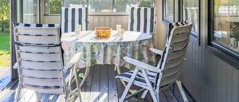 A covered outdoor patio with a round table and chairs, a bowl, and cups.