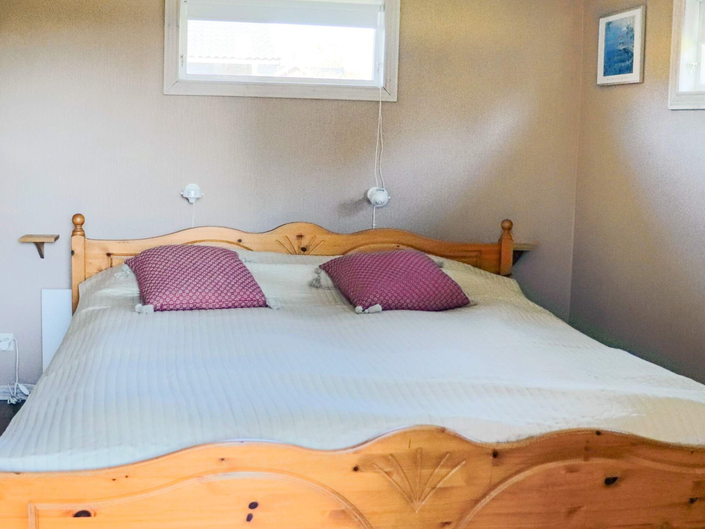 A bed with a wooden headboard, two pillows, and a white bedspread.