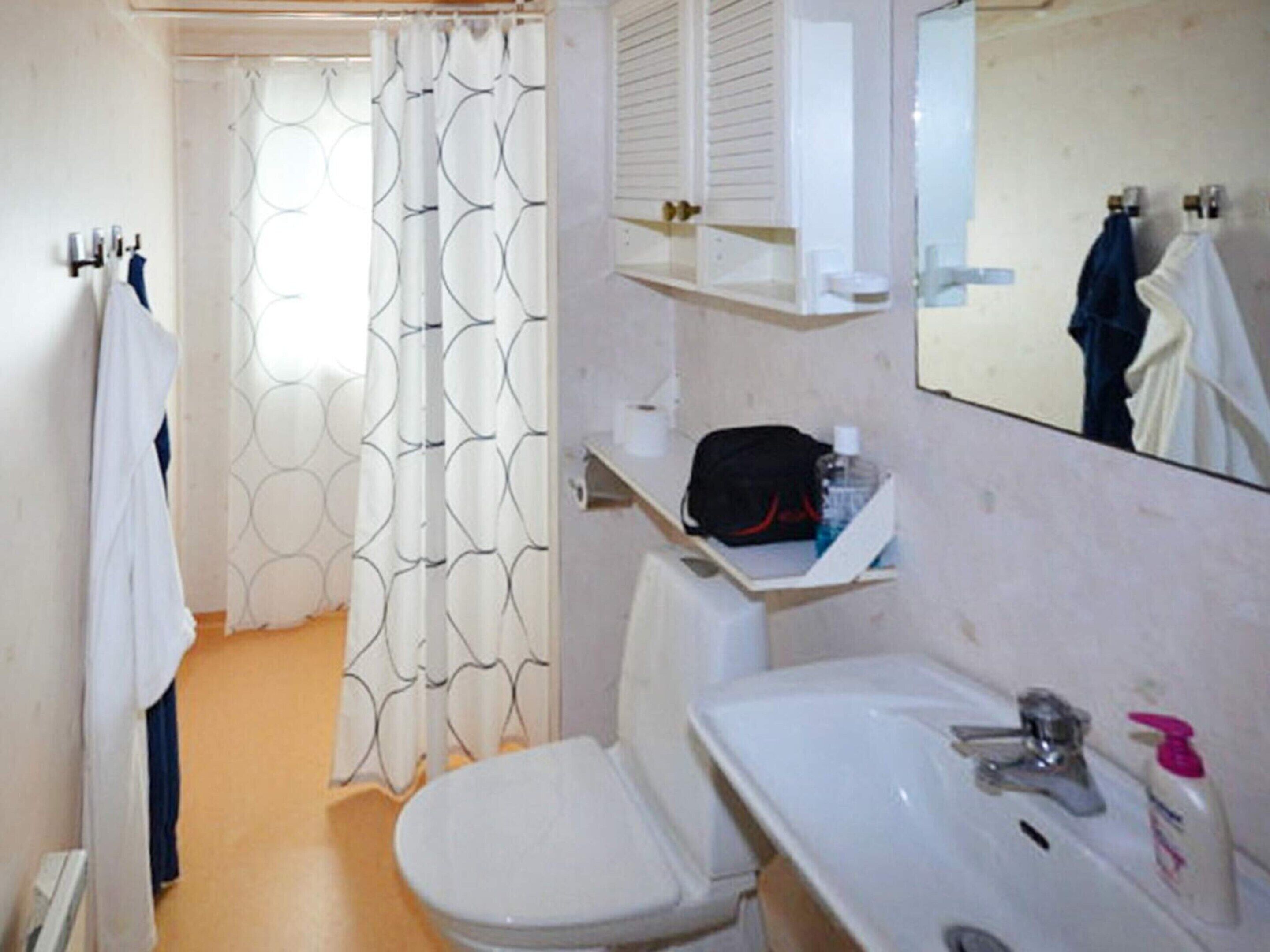 Een badkamer met toilet, wastafel en douchegordijn.